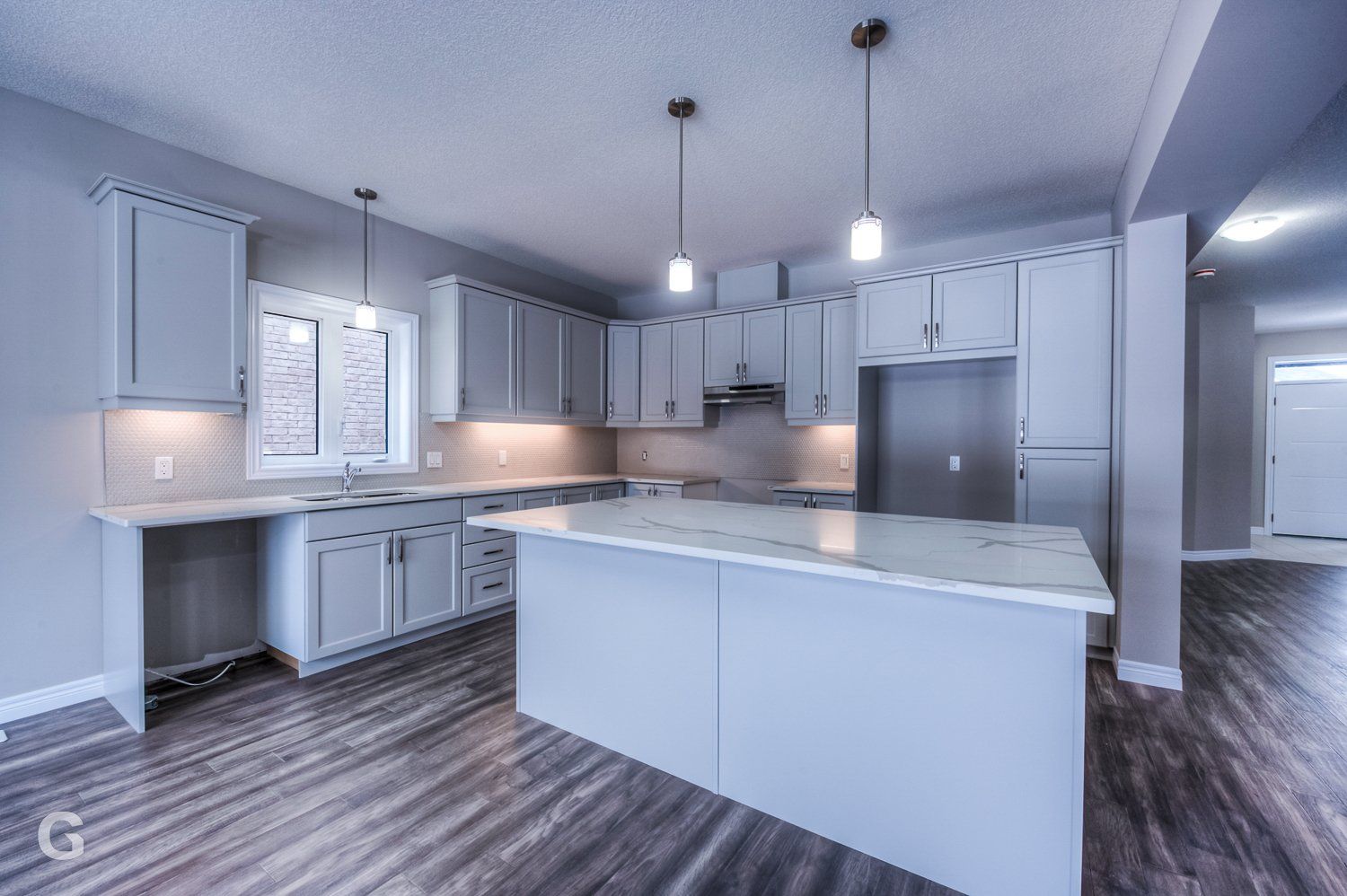 An empty kitchen with white cabinets and a large island.