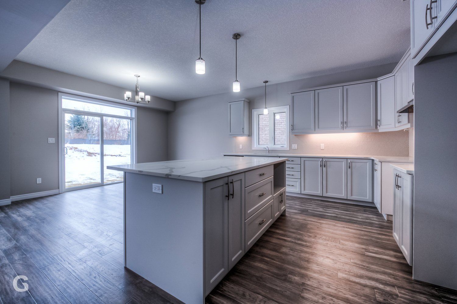 An empty kitchen with white cabinets and a large island.