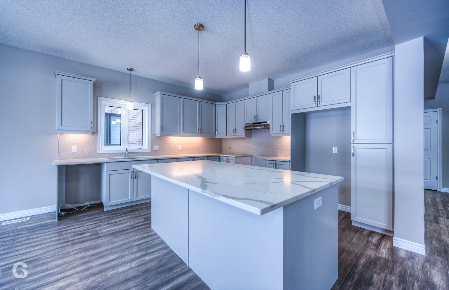 An empty kitchen with white cabinets and a large island in the middle.