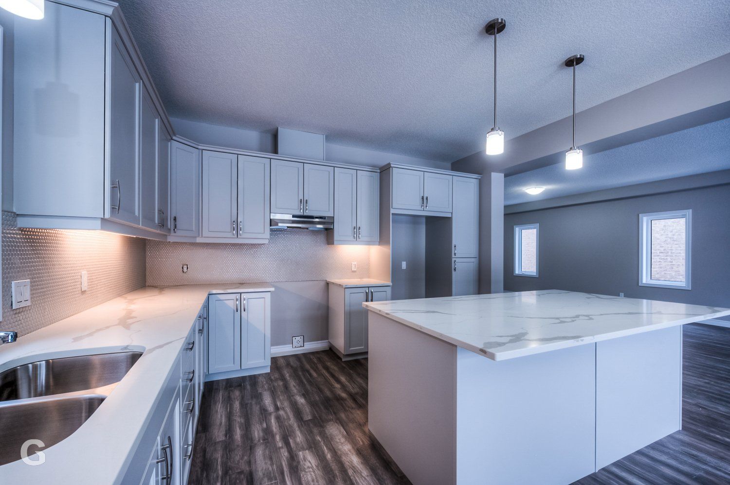 An empty kitchen with white cabinets and a large island.