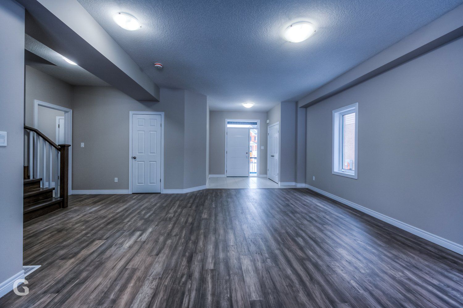 An empty living room with hardwood floors and a staircase.