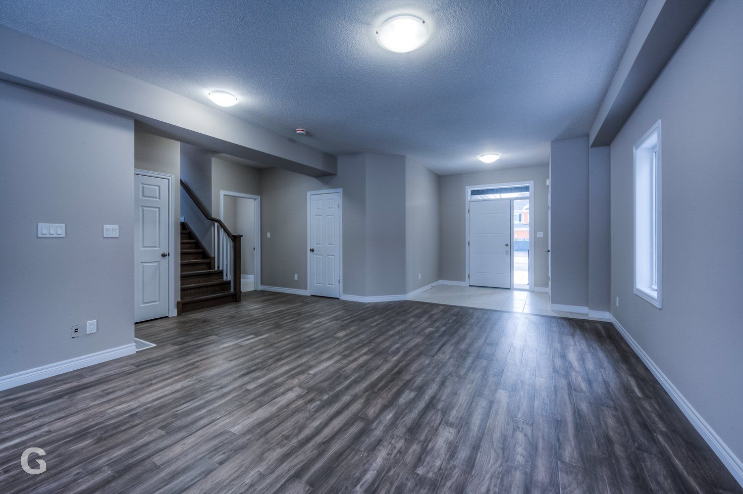 An empty living room with hardwood floors and stairs in a house.
