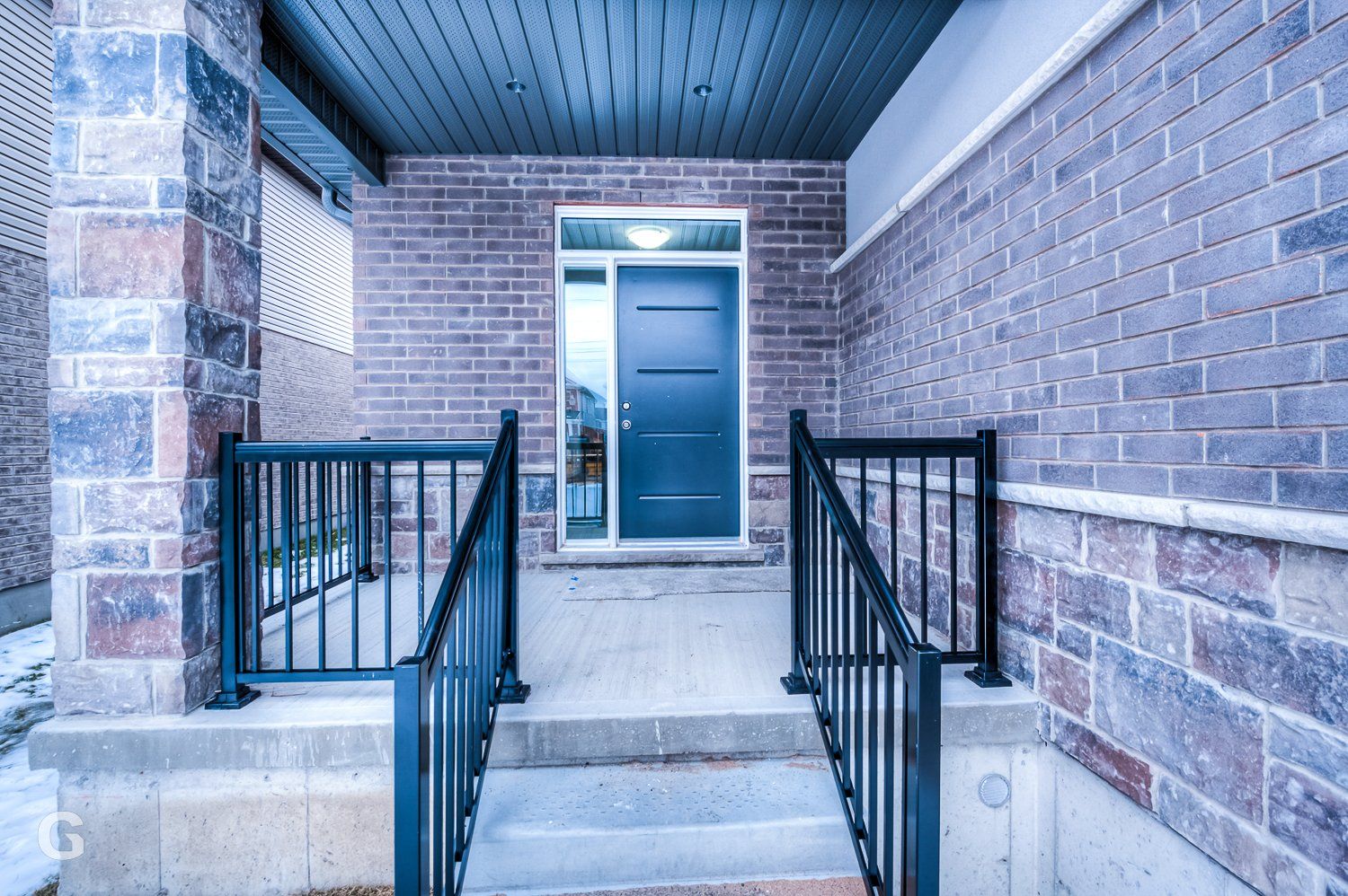 A brick house with a blue door and stairs leading to it.