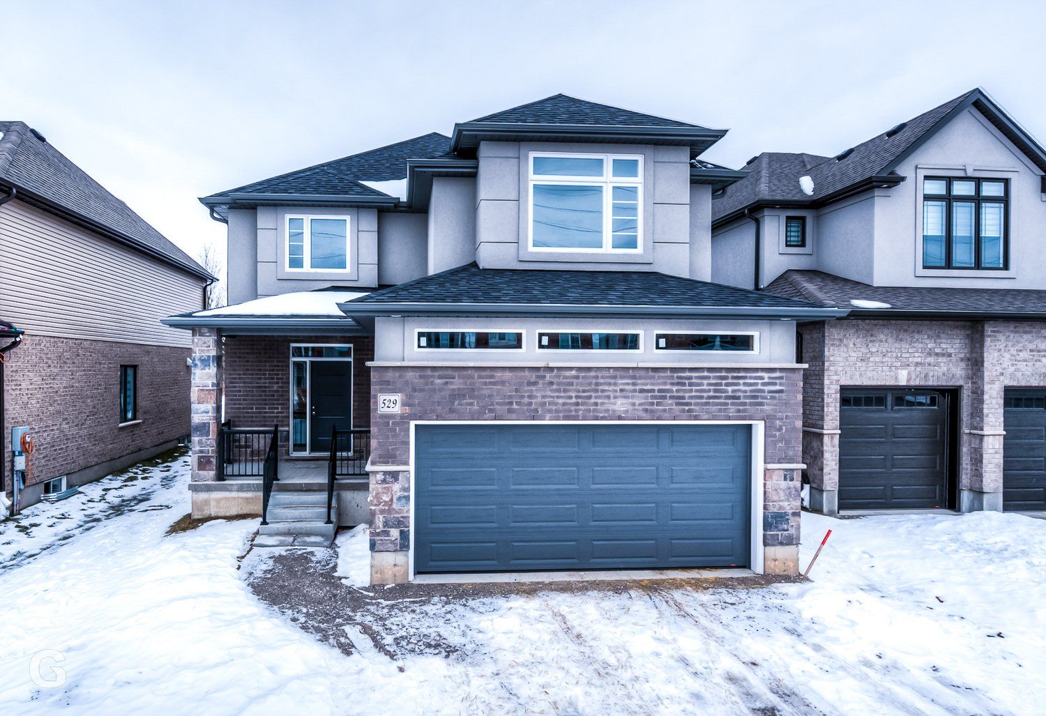 A large house with a garage and a lot of snow on the ground.
