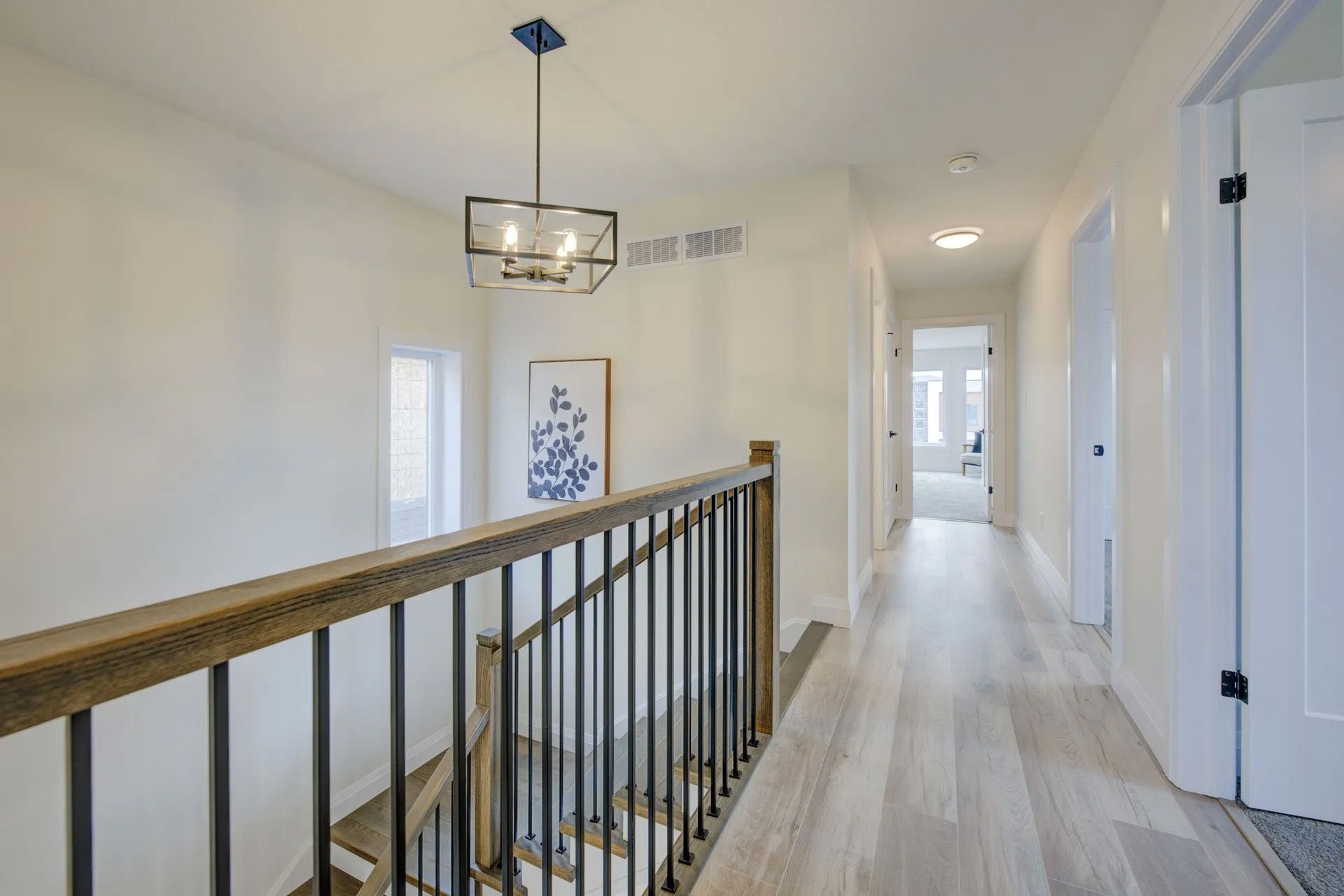 A hallway with stairs and a railing in a house.