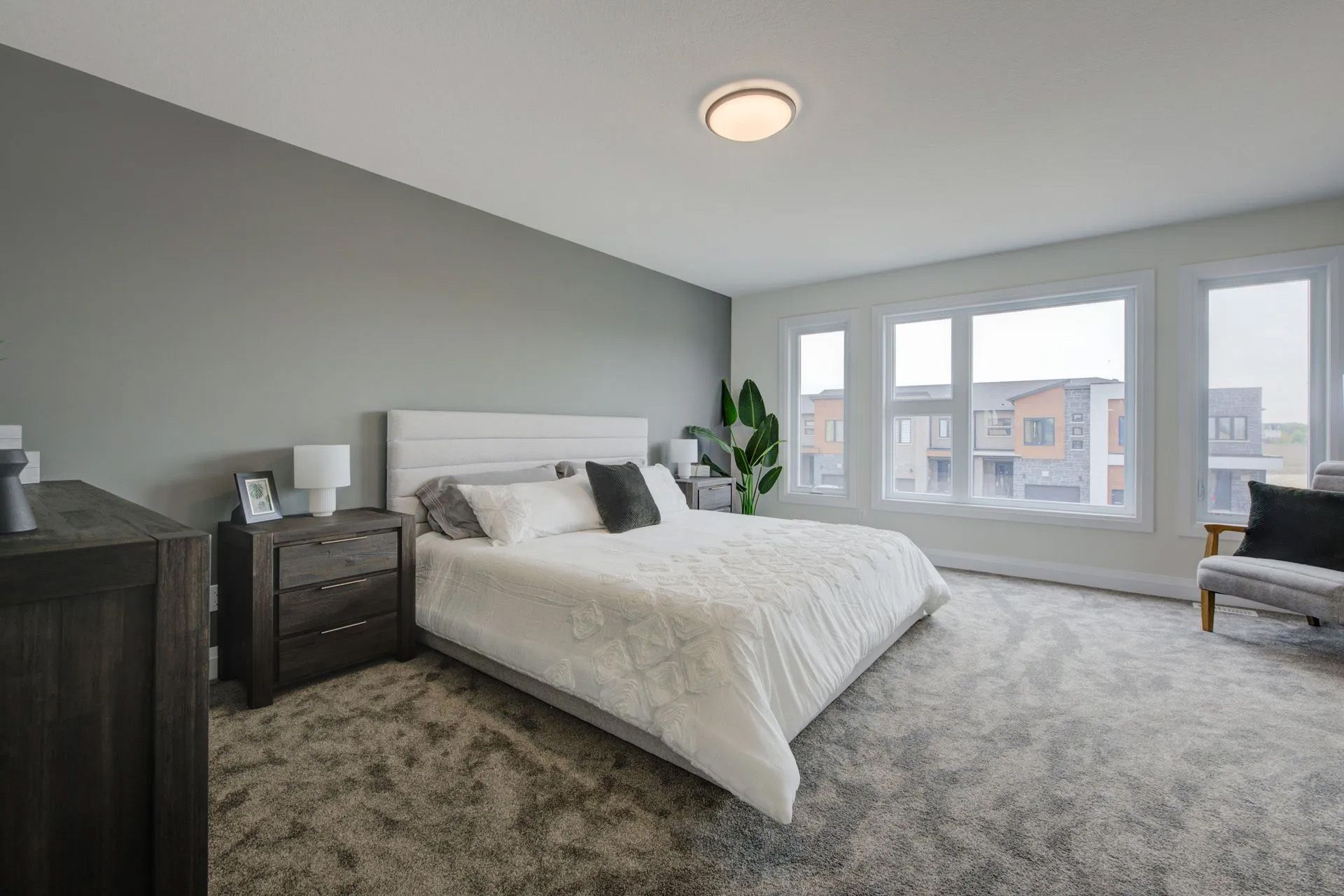 A bedroom with a large bed , dresser , nightstand and chair.