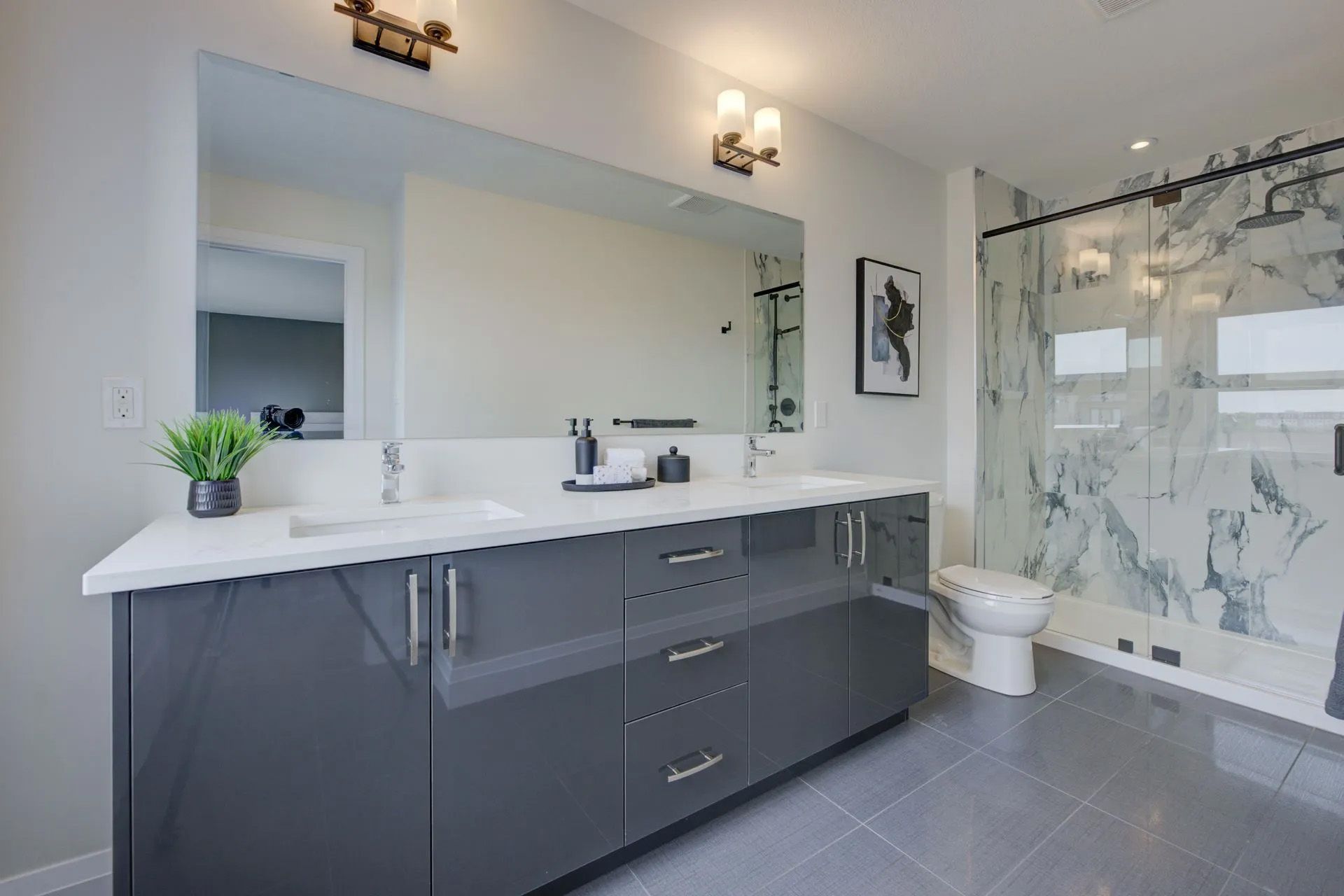 A bathroom with two sinks , a toilet , and a large mirror.