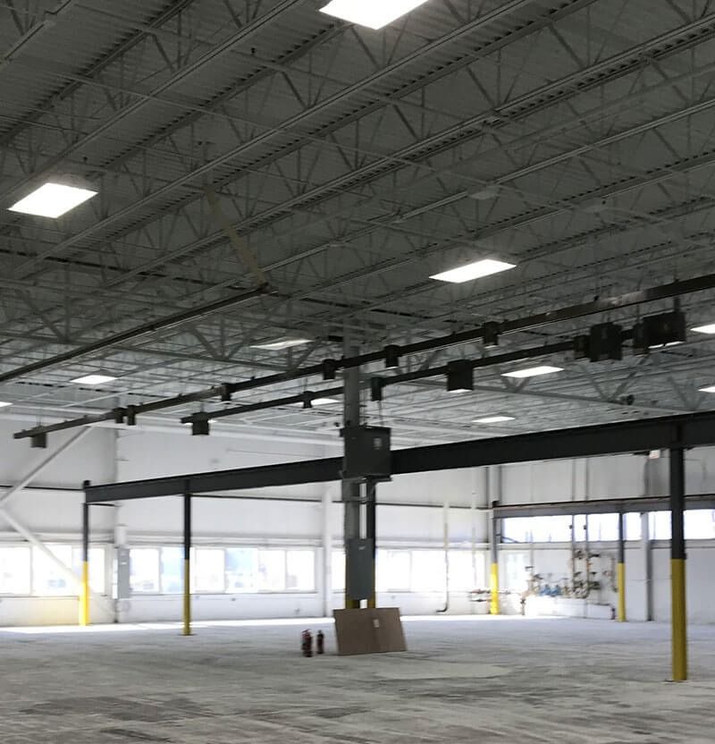 Empty warehouse interior with steel beams, skylights, and concrete floor.