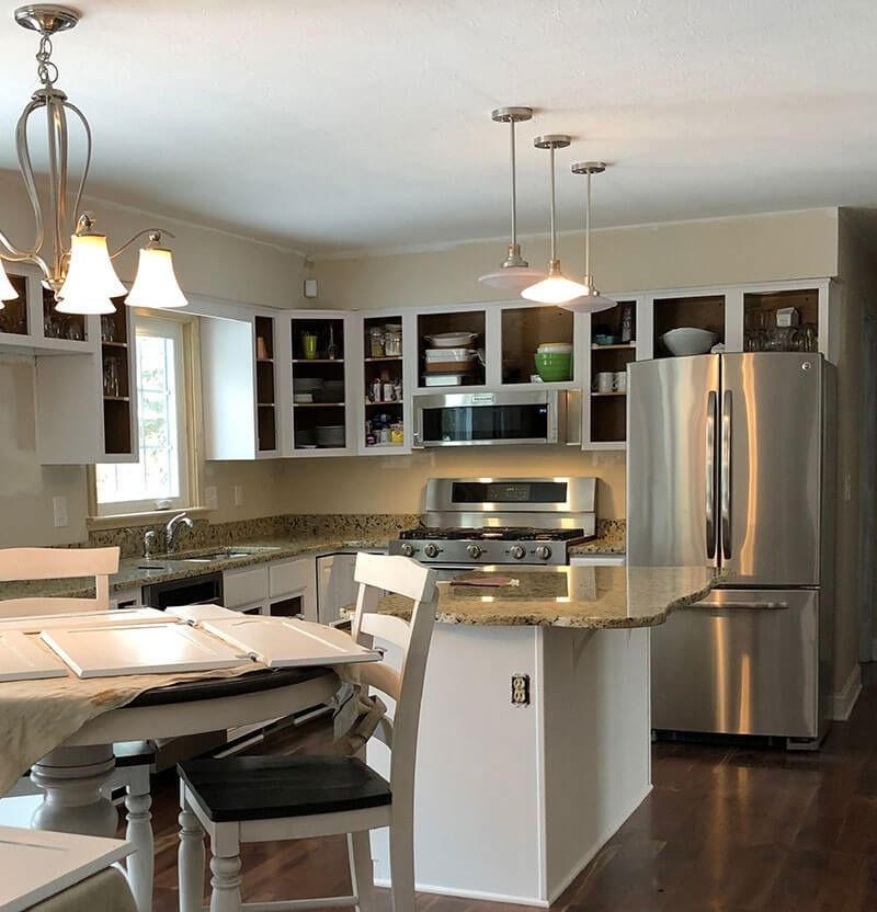 Kitchen with white cabinets, granite countertops, stainless steel appliances, and a small island.