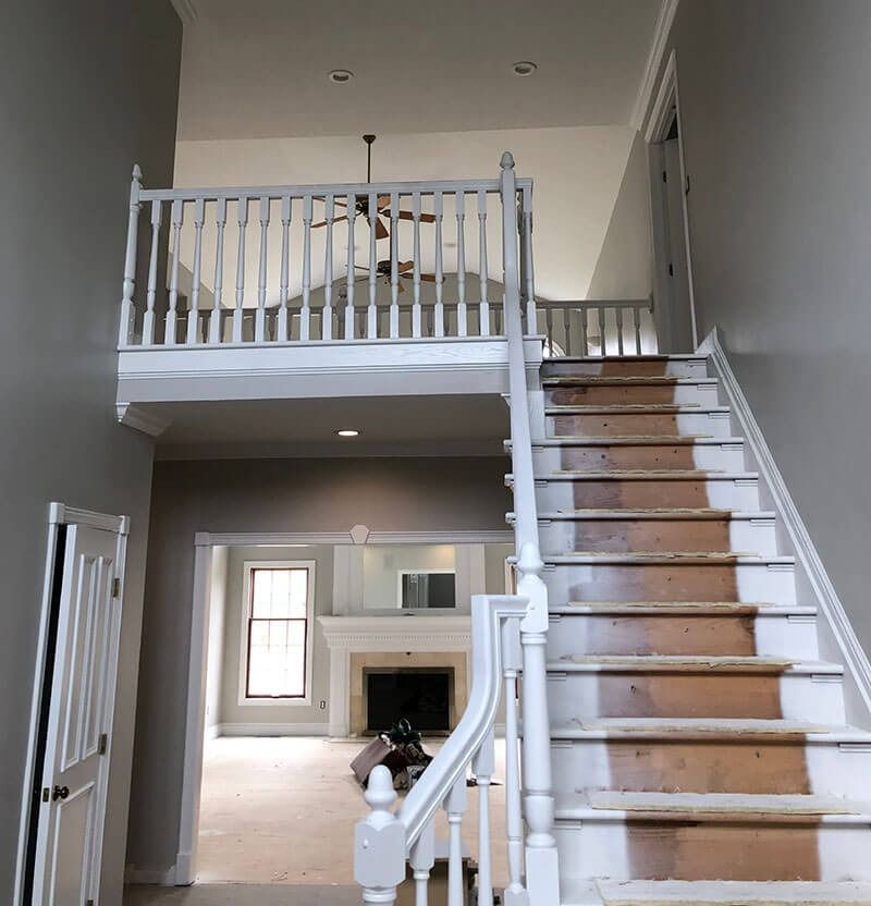 Interior view of a house with staircase, landing, and a white railing.