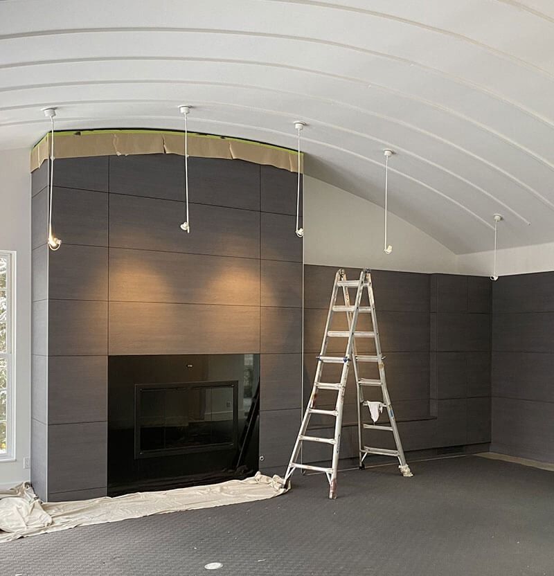 Fireplace construction: dark gray panels, black fireplace, ladder, white lights, arched ceiling.