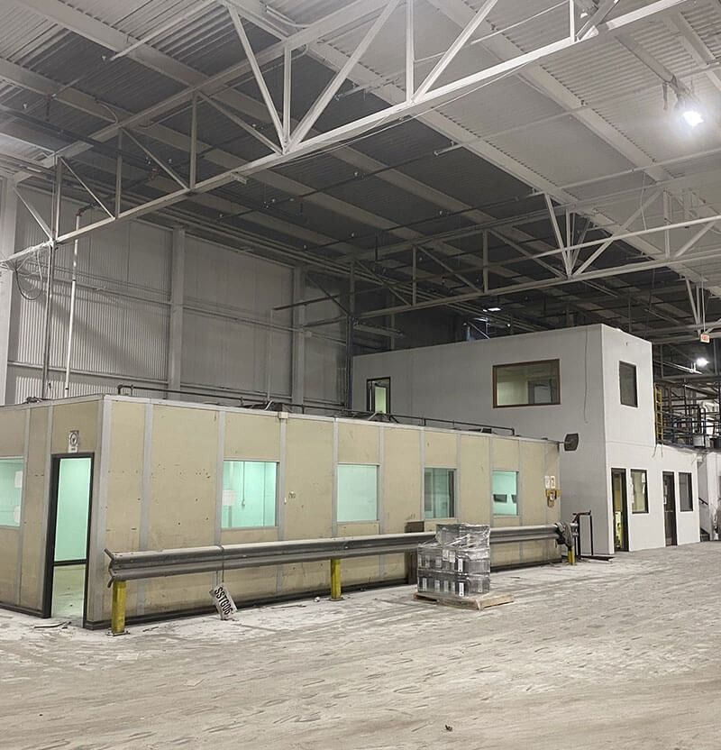 Warehouse interior with modular structures, concrete floor, and metal roof.