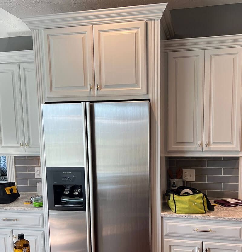 White kitchen cabinets surround a stainless steel refrigerator.