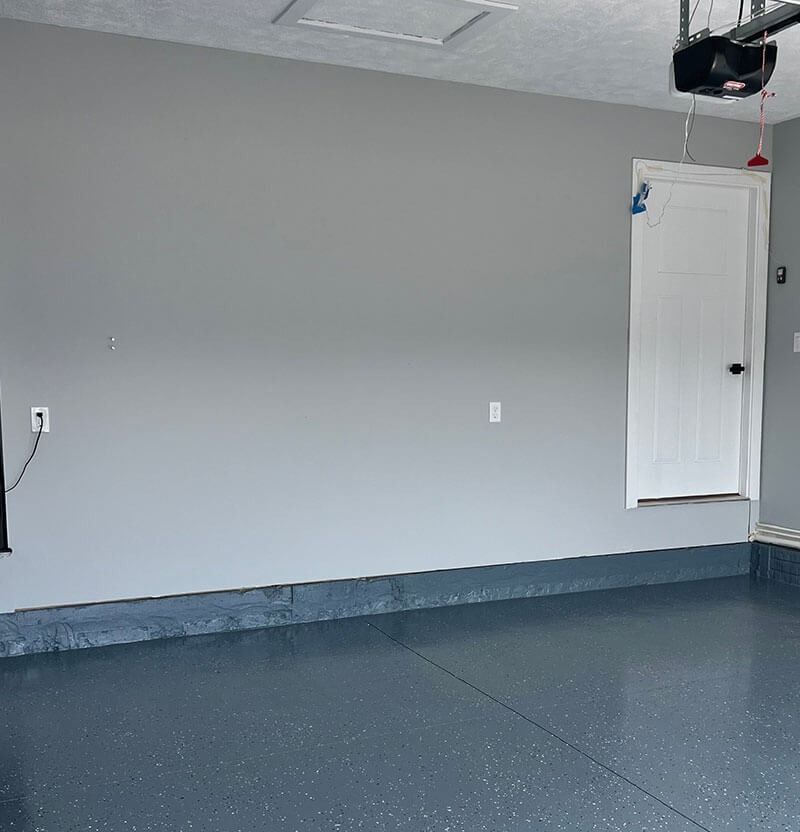 Gray-painted garage with a white door and a speckled blue floor.