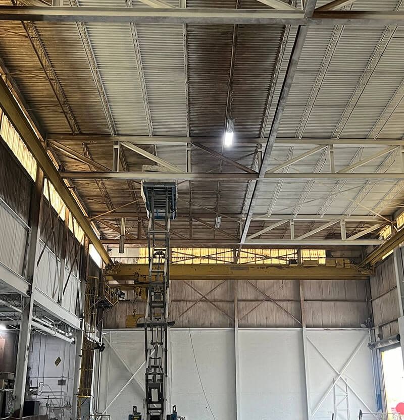 Interior of a warehouse with scaffolding; roof shows contrast between clean and dirty areas.