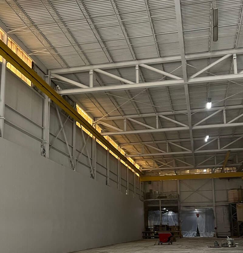 Inside view of a large white warehouse, with yellow support beams.