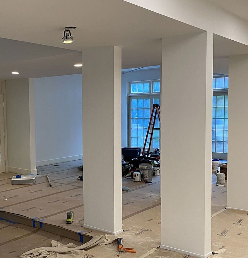 Interior view: White walls, columns, construction in progress, ladder near windows.