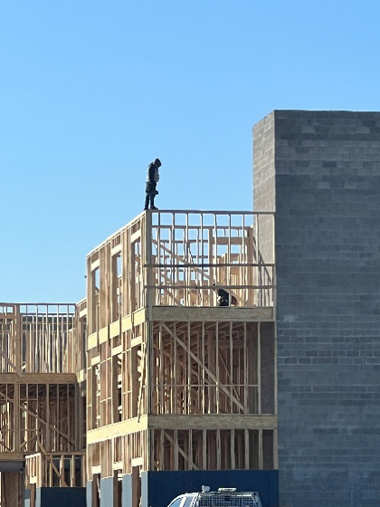 A man is standing on top of a building under construction