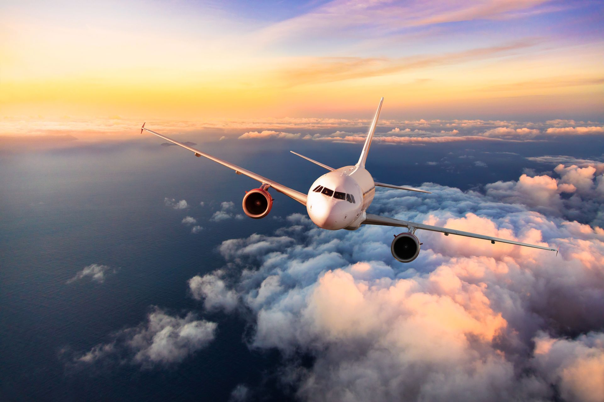 A large passenger jet is flying through the clouds at sunset.