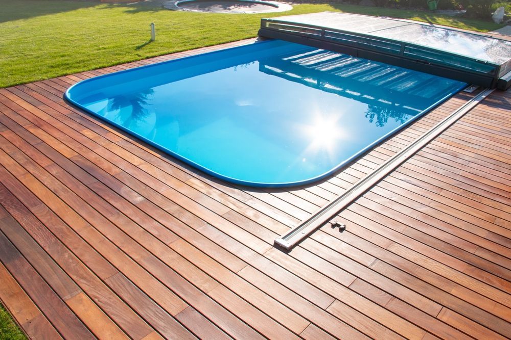Woman in straw hat smiles, holding wine glass near a lake.