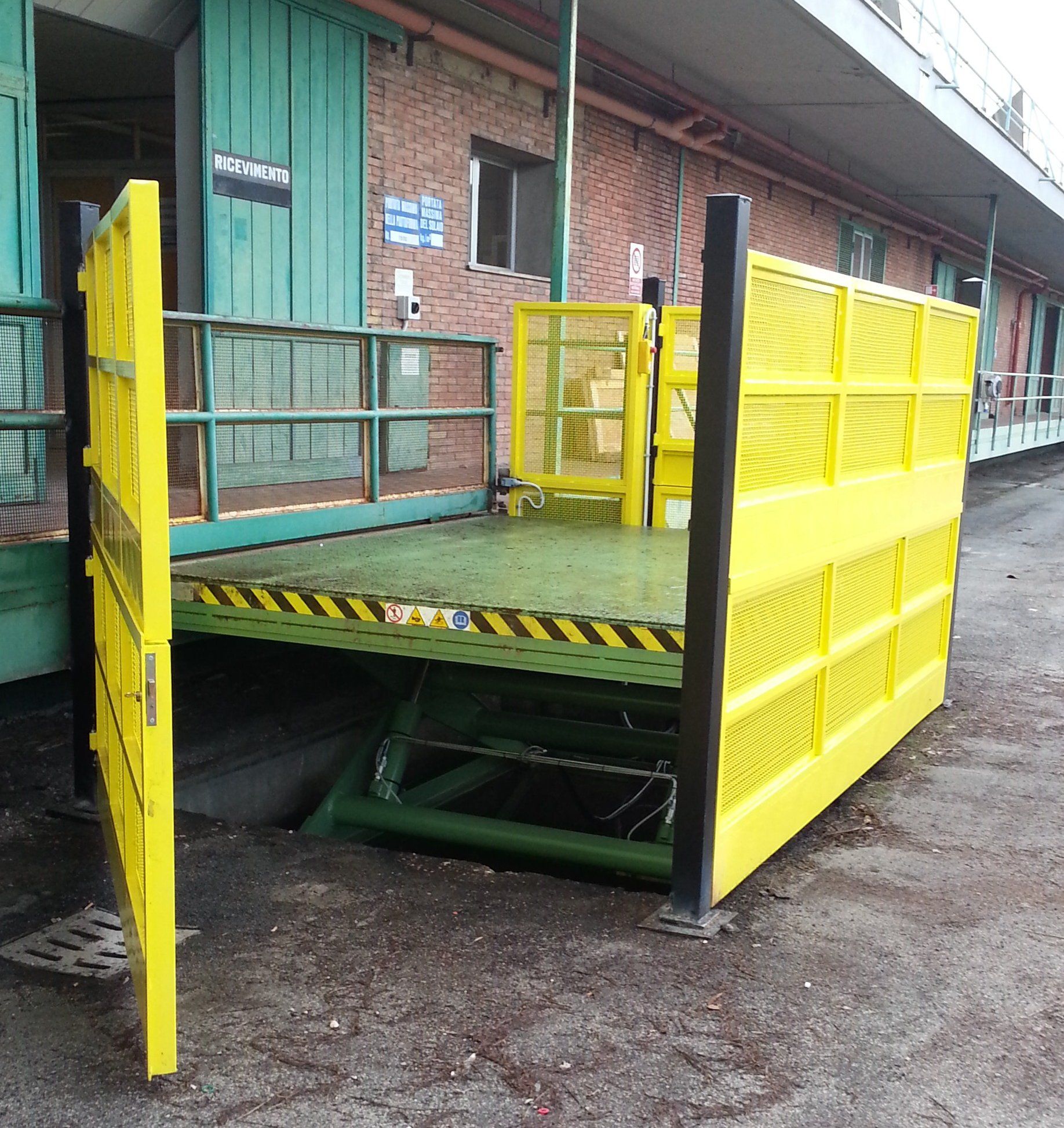 Una recinzione gialla circonda un montacarichi davanti a un edificio