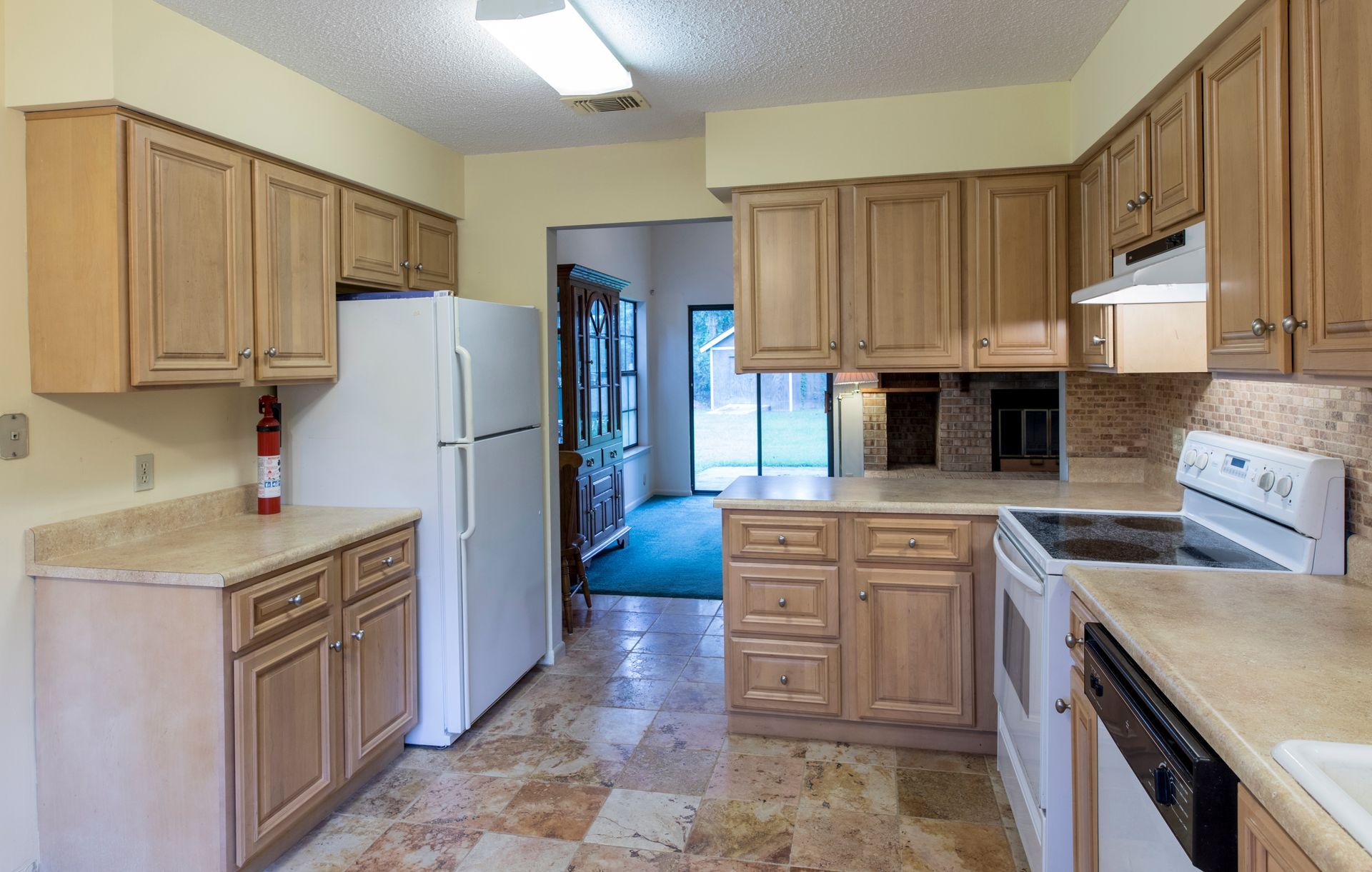 Kitchen with light wood cabinets, white appliances, and tiled floor.
