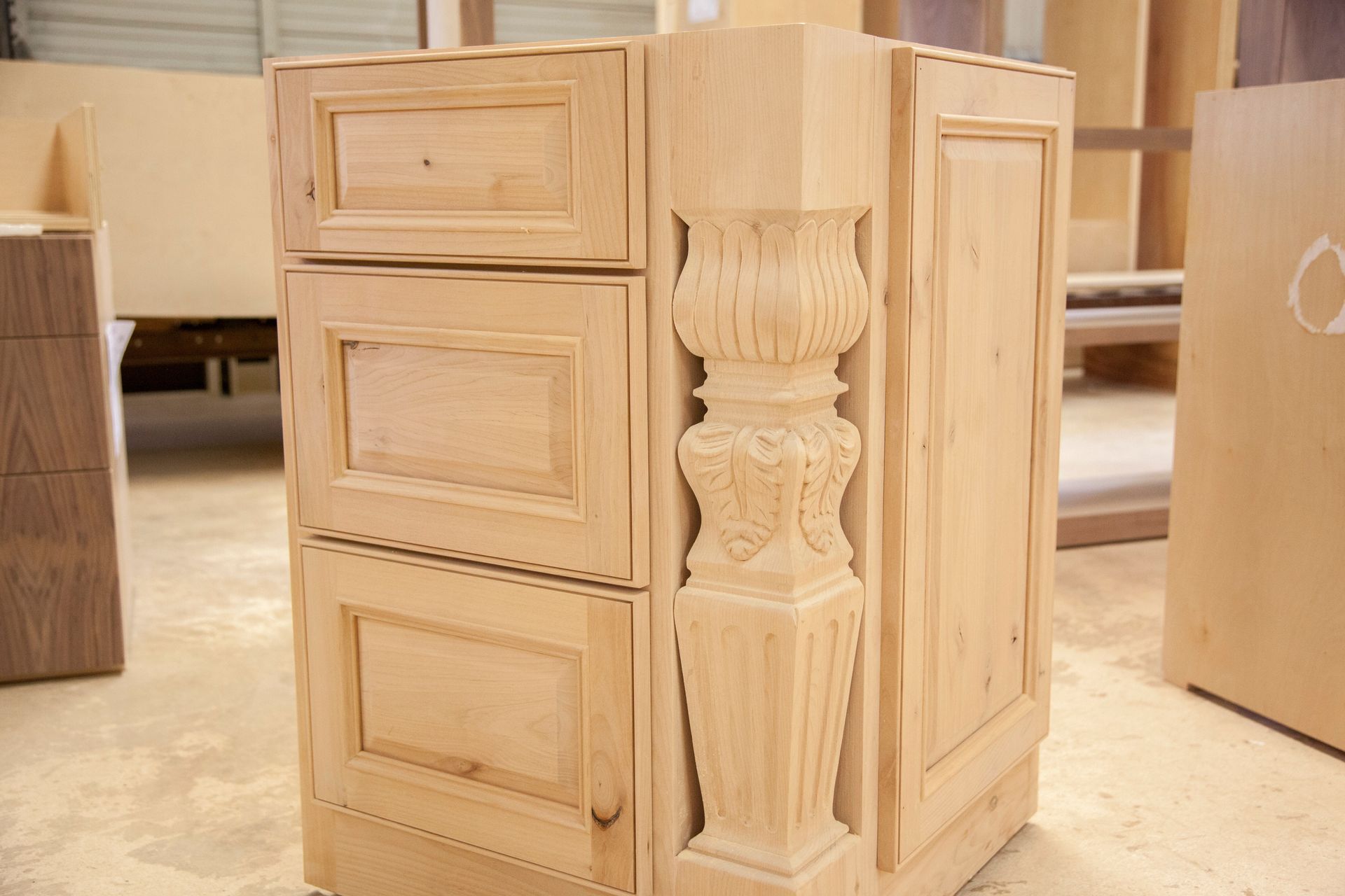 Wooden cabinet unit with decorative column in a workshop setting.