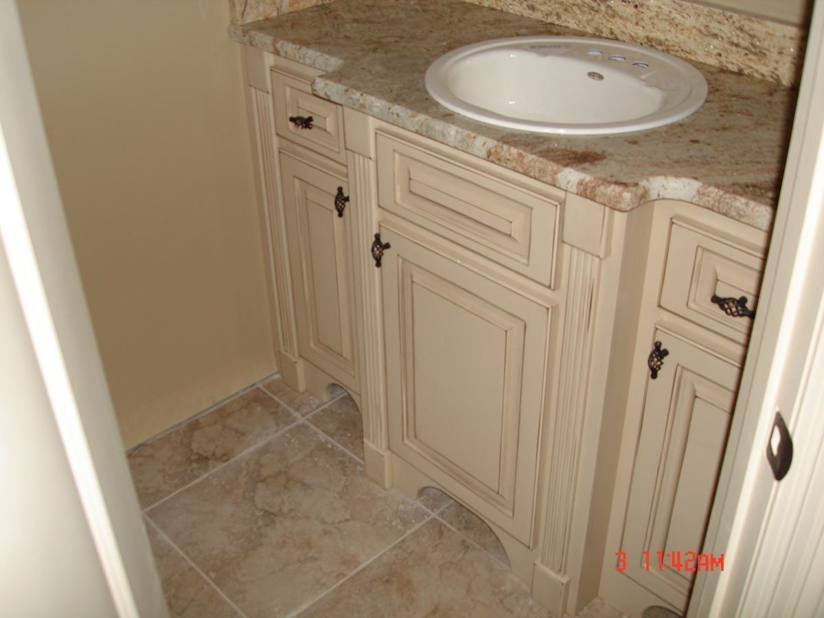 Beige bathroom vanity with a granite countertop and oval sink.