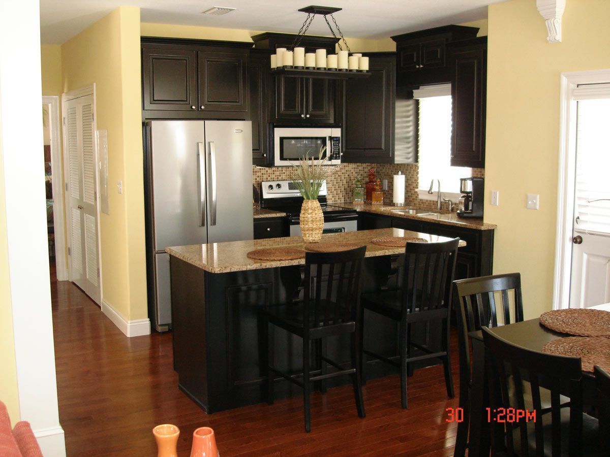 Kitchen with dark cabinets, stainless steel appliances, and island with seating.