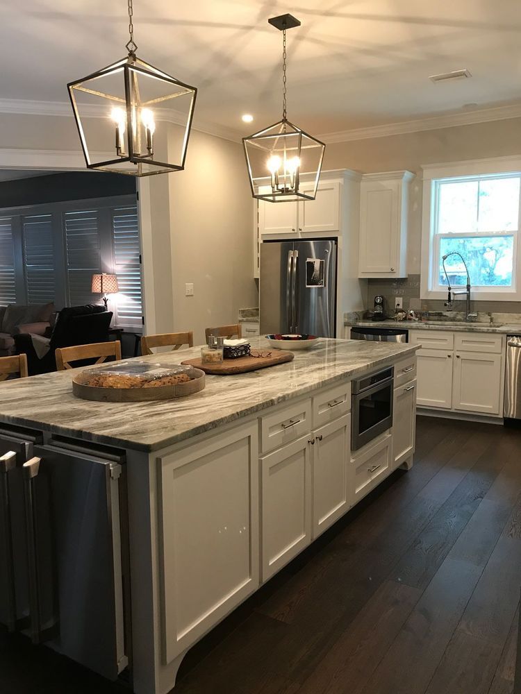 Modern kitchen with a large island, stainless steel appliances, and two hanging lights.