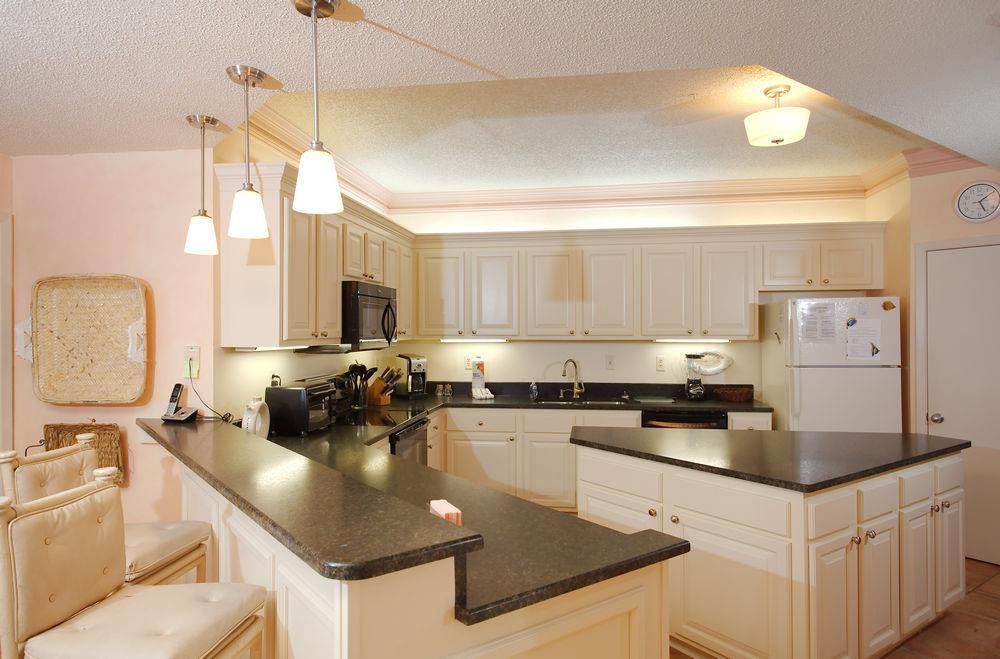 Cream-colored kitchen with black countertops, pendant lights, and an island.