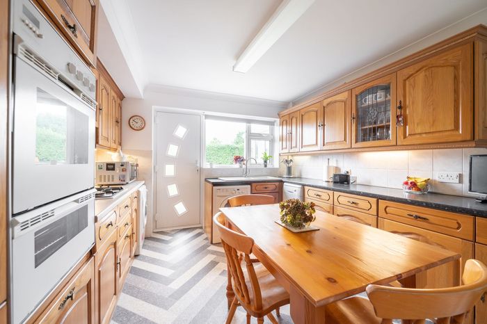 A kitchen with wooden cabinets , a table and chairs.