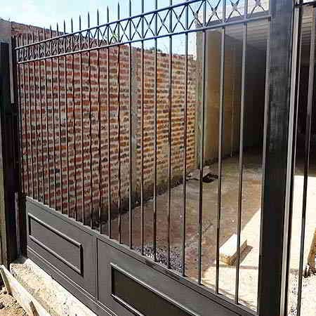 Puerta y valla de metal negro contra una pared de ladrillo.