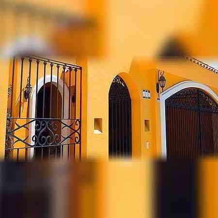 Edificio amarillo con verjas de hierro forjado negras.