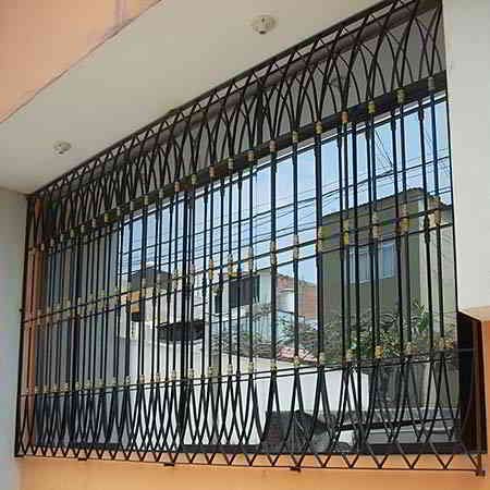 Rejas de seguridad de metal negro en una ventana, con vistas a una calle con edificios.