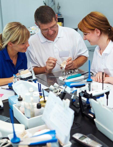 a man and two women are sitting at a table looking at something