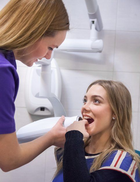 a woman is getting her teeth examined by a dentist