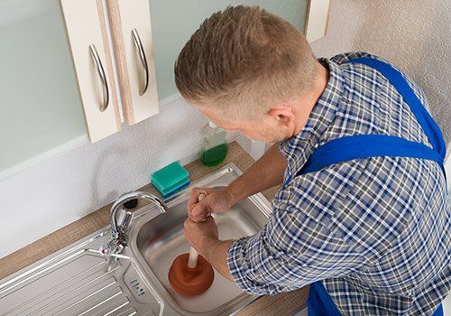 Drain Cleaning — Man cleaning kitchen sink  in South Yarmouth, MA