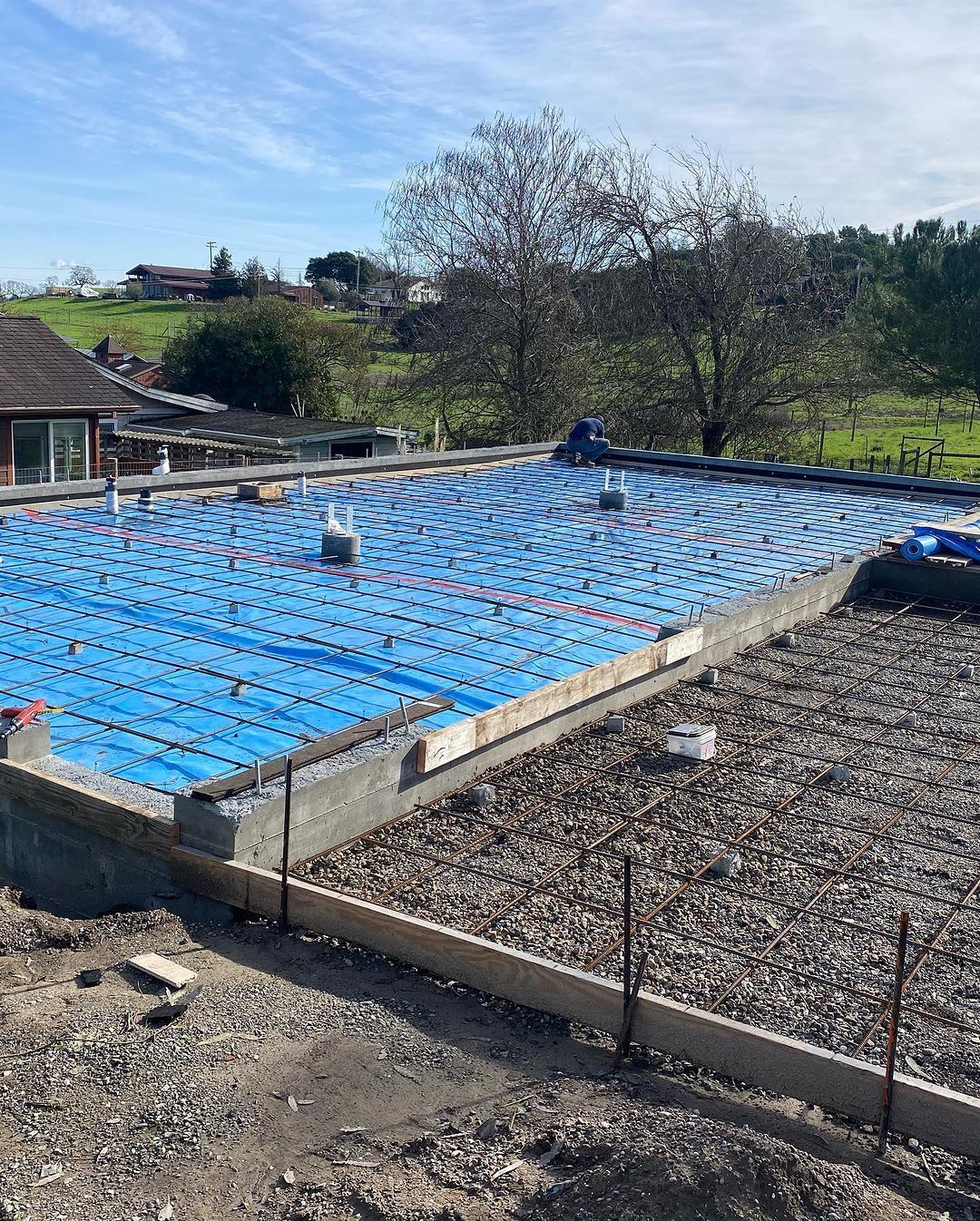 A swimming pool is being built on top of a dirt field.