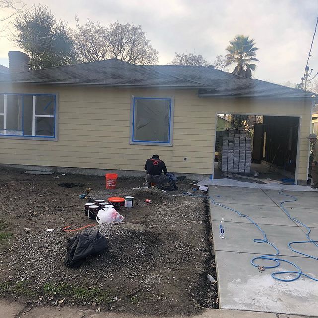 A man is sitting in front of a yellow house