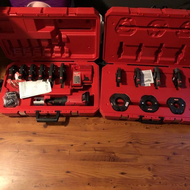 Two red cases filled with tools on a wooden table