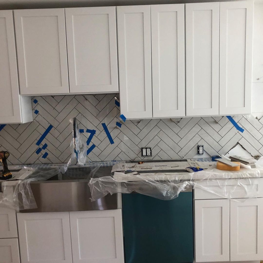 A kitchen with white cabinets and a stainless steel sink