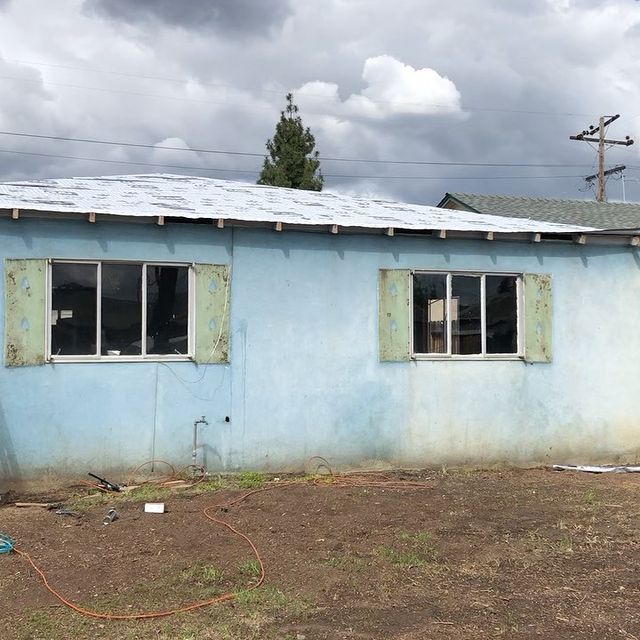 A blue house with a roof and shutters on the windows