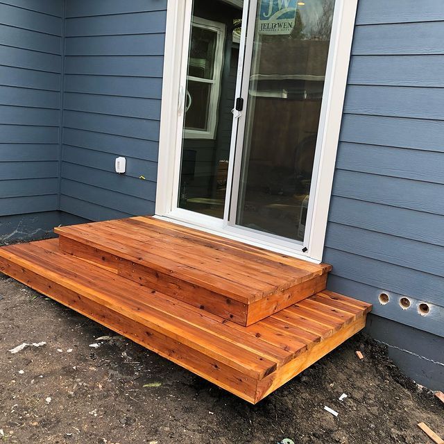 A blue house with a wooden deck in front of it