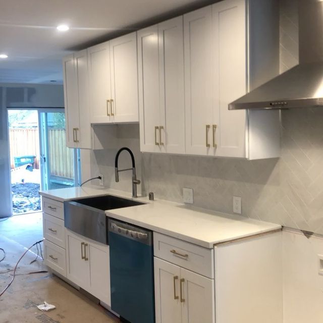 A kitchen with white cabinets and a stainless steel dishwasher