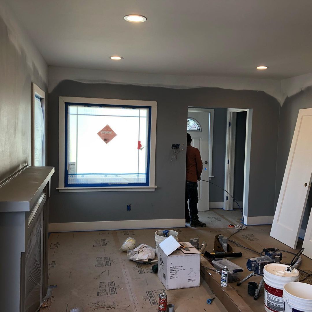 A living room with a man standing in the doorway and a window.