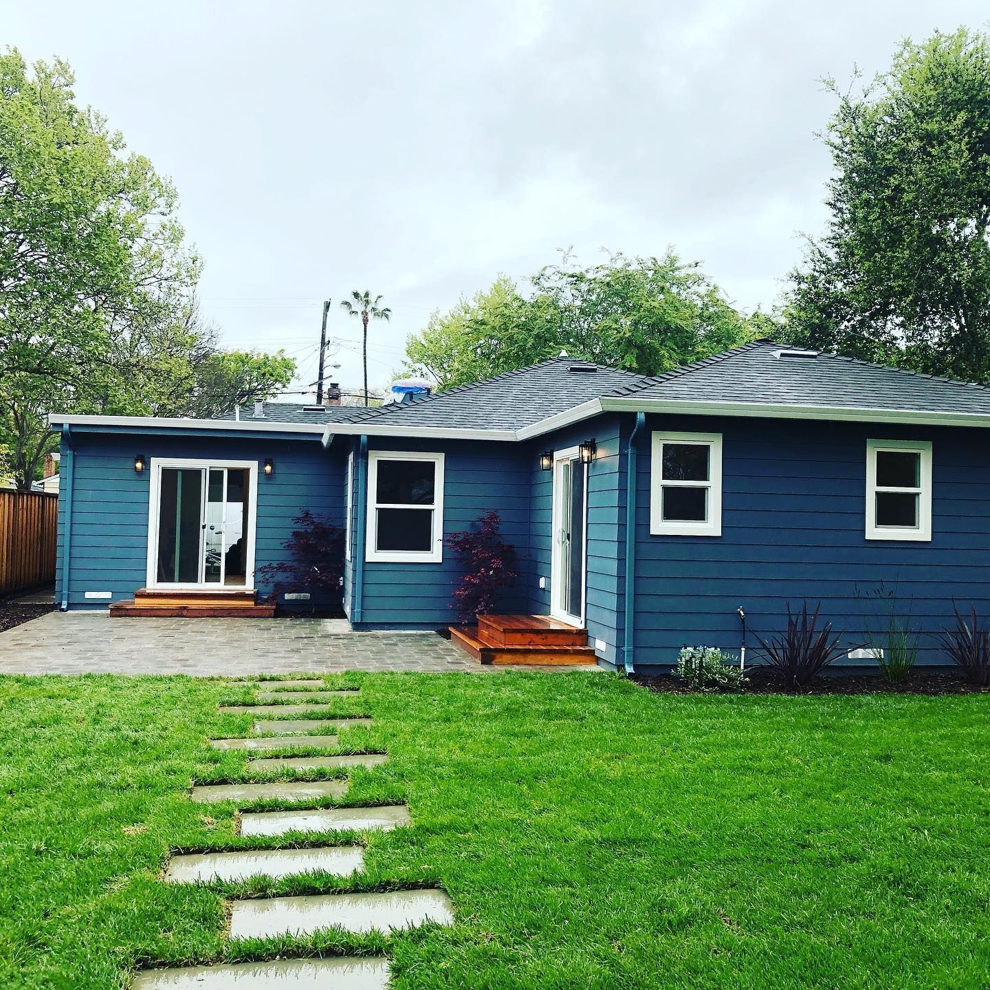 A blue house with a lush green lawn in front of it