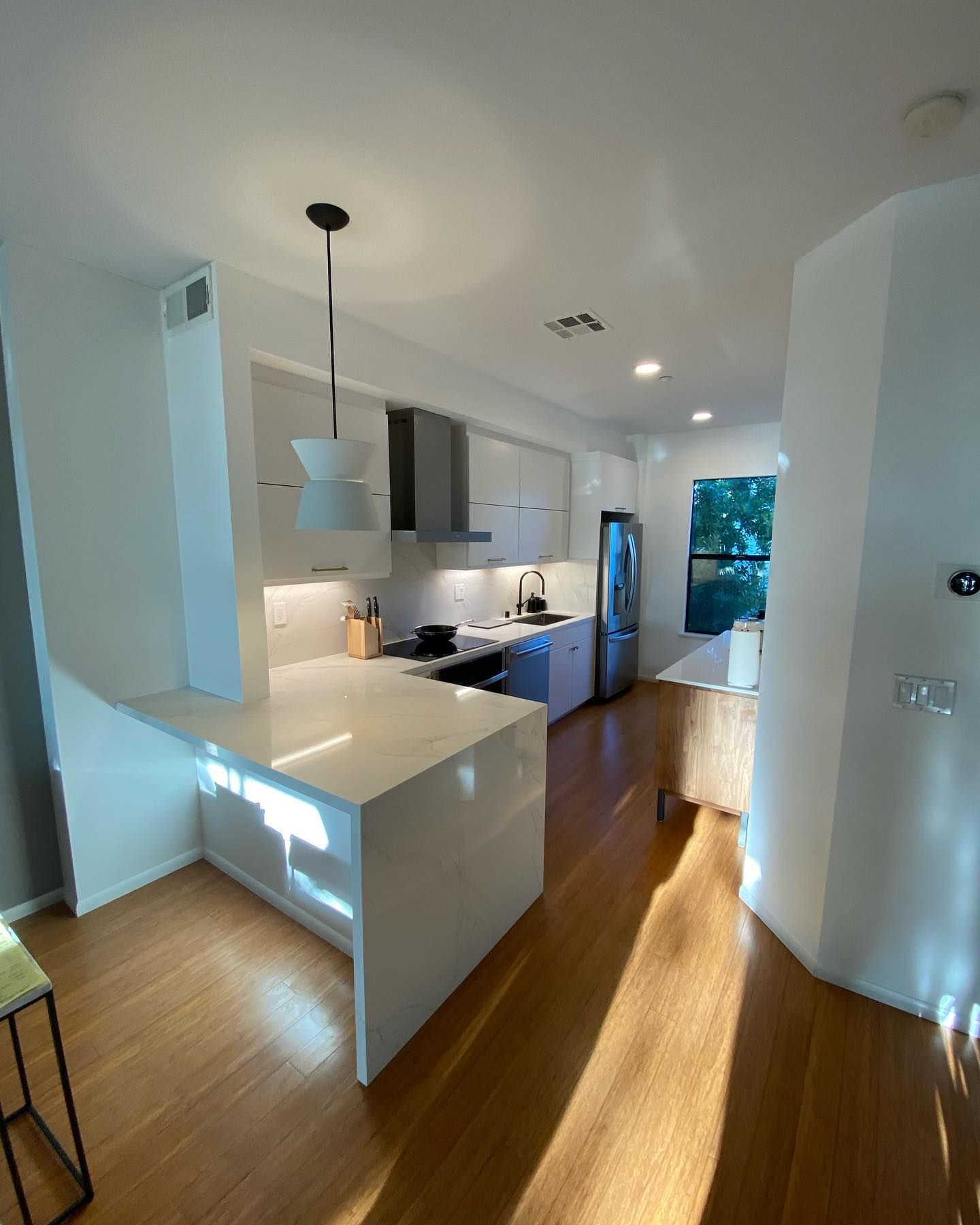 A kitchen with white cabinets and a wooden floor
