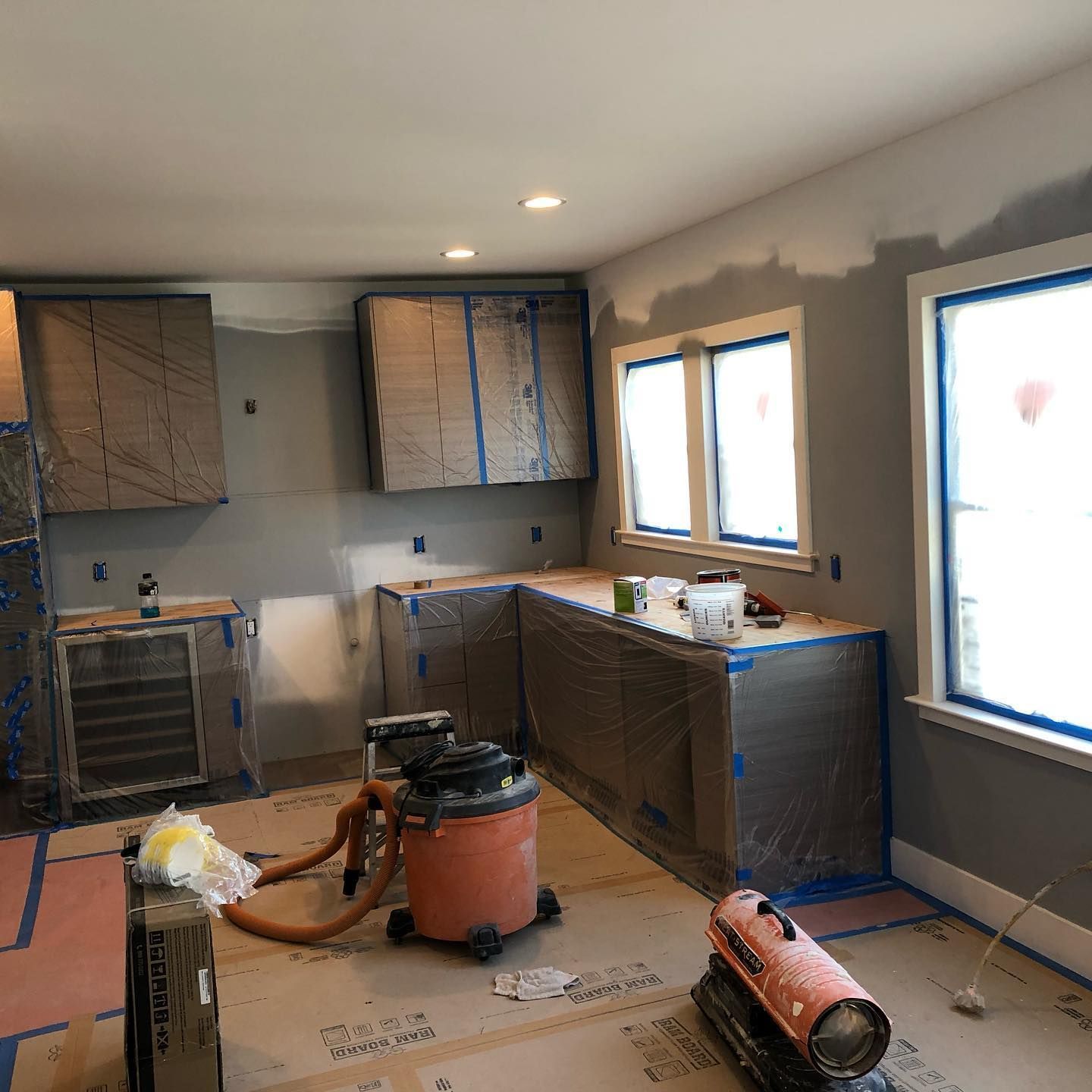 A kitchen under construction with a vacuum cleaner and heater on the floor.