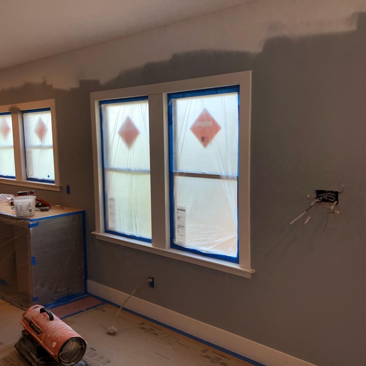 A room with two windows and a heater in it.